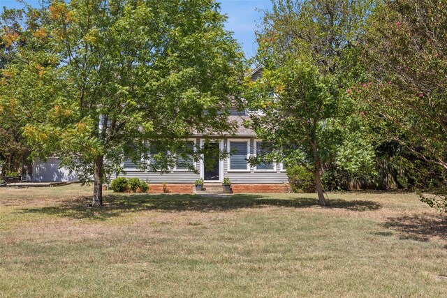 view of property hidden behind natural elements featuring a front yard