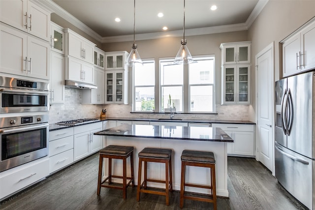 kitchen with appliances with stainless steel finishes, backsplash, dark hardwood / wood-style floors, and a center island