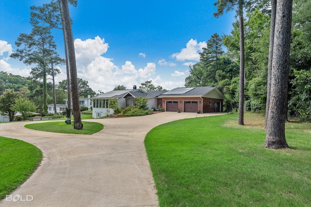 ranch-style home with a front lawn, solar panels, and a garage