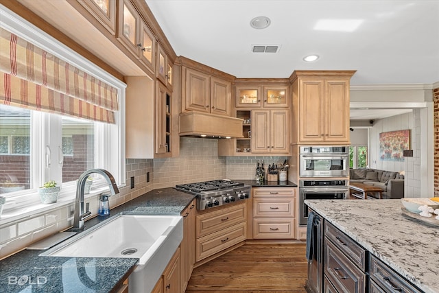 kitchen featuring appliances with stainless steel finishes, sink, wood-type flooring, and dark stone counters