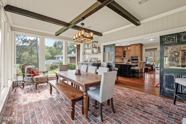 dining space with a chandelier, ornamental molding, brick floor, and beam ceiling