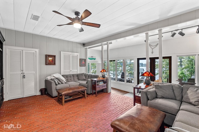 living area with plenty of natural light, ceiling fan, brick floor, and visible vents