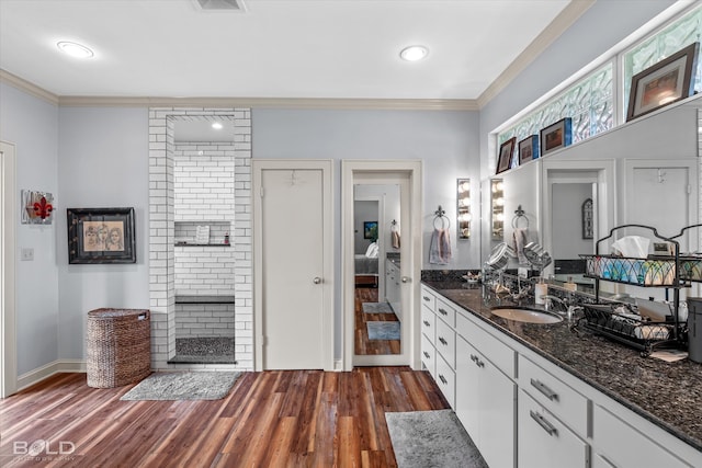 kitchen with crown molding, dark hardwood / wood-style flooring, white cabinets, sink, and dark stone counters