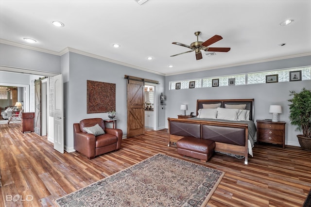 bedroom with ceiling fan, a barn door, hardwood / wood-style flooring, and ornamental molding