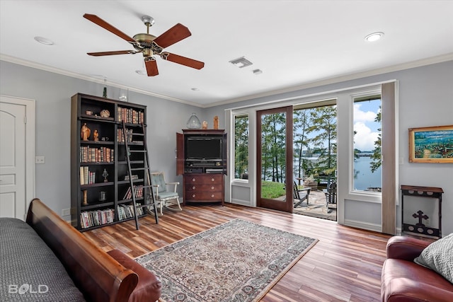 living area featuring a ceiling fan, wood finished floors, visible vents, and crown molding