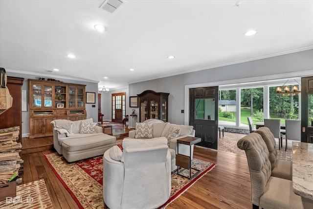 living room featuring an inviting chandelier, ornamental molding, and hardwood / wood-style flooring