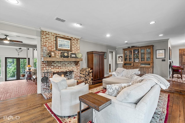 living room with ornamental molding, hardwood / wood-style flooring, a brick fireplace, ceiling fan, and brick wall