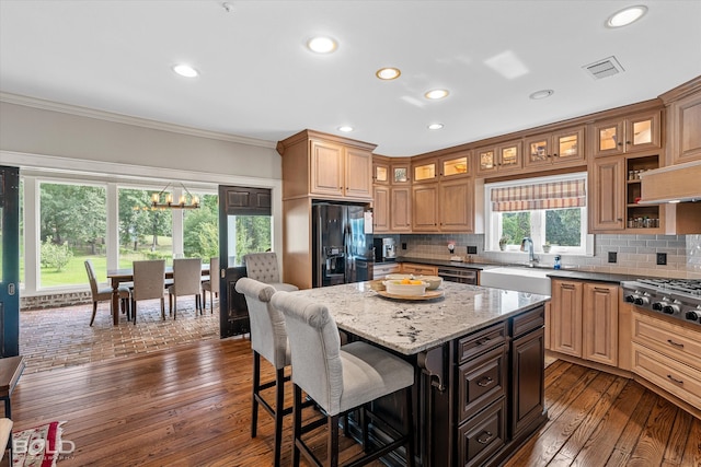 kitchen featuring dark hardwood / wood-style floors, a kitchen island, black fridge, and backsplash