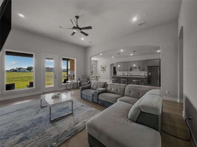 living room featuring arched walkways, wood finished floors, visible vents, and recessed lighting