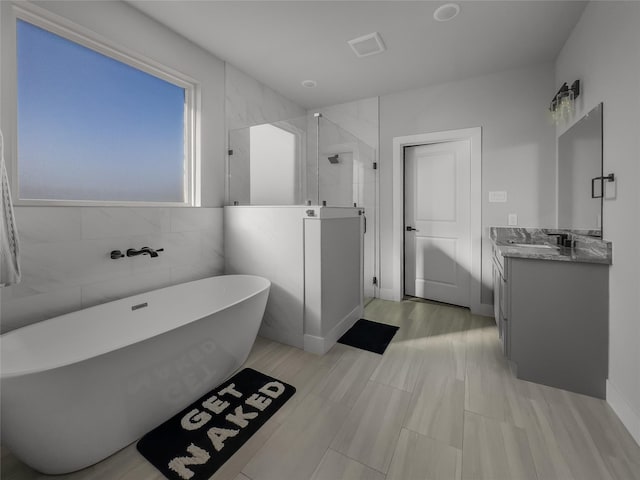 bathroom featuring a freestanding bath, vanity, a shower stall, and visible vents