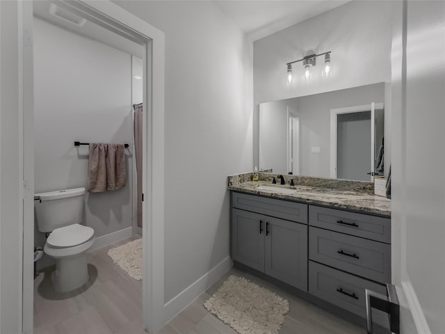 bathroom featuring toilet, a shower with curtain, baseboards, and vanity