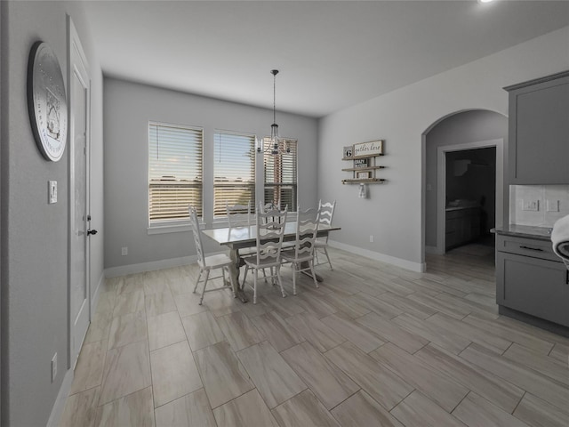 dining space with baseboards and arched walkways