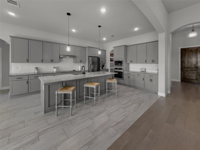 kitchen featuring hanging light fixtures, a large island, appliances with stainless steel finishes, and gray cabinets