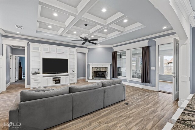 living room with a high end fireplace, light wood-type flooring, ceiling fan, and coffered ceiling