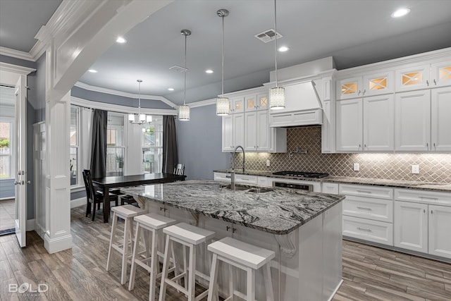 kitchen with white cabinets, custom exhaust hood, tasteful backsplash, decorative light fixtures, and a wealth of natural light