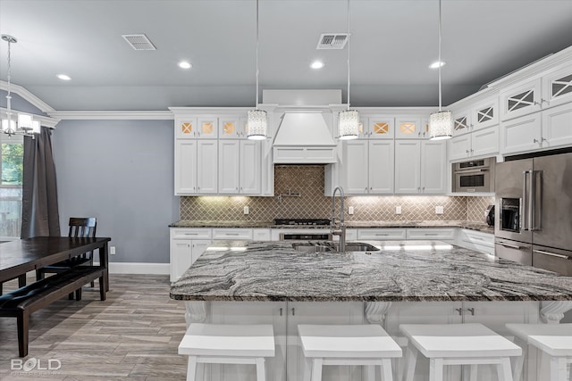 kitchen with appliances with stainless steel finishes, a spacious island, tasteful backsplash, and decorative light fixtures