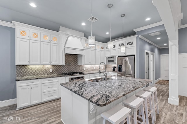 kitchen with white cabinetry, appliances with stainless steel finishes, crown molding, custom range hood, and backsplash