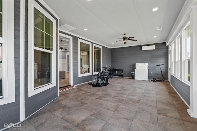 unfurnished sunroom featuring ceiling fan and a wall mounted AC