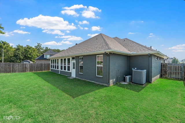 back of house with central air condition unit, a sunroom, and a yard