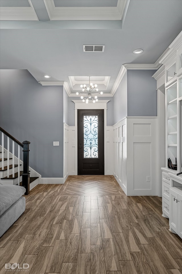 entrance foyer featuring an inviting chandelier, a tray ceiling, crown molding, and wood-type flooring