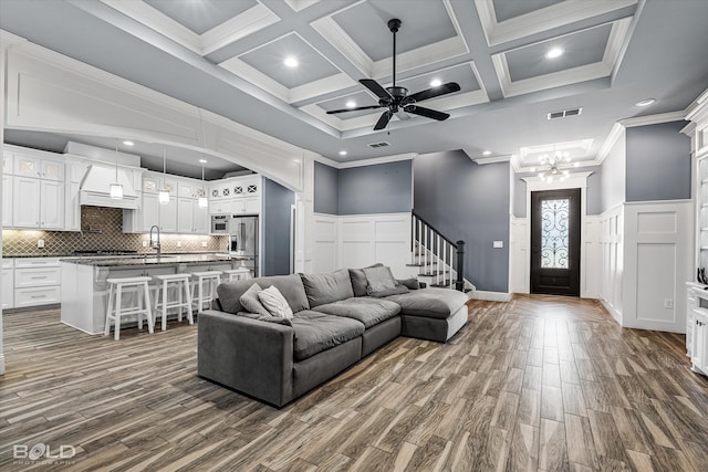 living room featuring coffered ceiling, ceiling fan, beam ceiling, a high ceiling, and hardwood / wood-style flooring