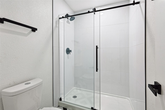 bathroom featuring toilet and a shower with shower door