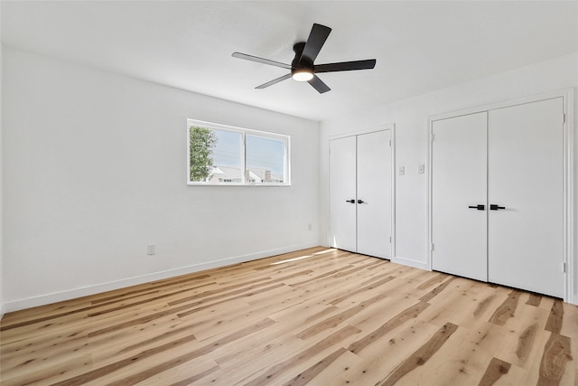 unfurnished bedroom with two closets, light hardwood / wood-style floors, and ceiling fan