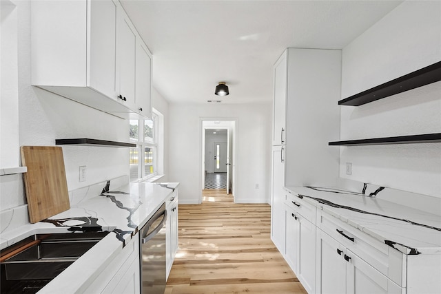 kitchen with dishwasher, light stone countertops, white cabinetry, and light hardwood / wood-style flooring