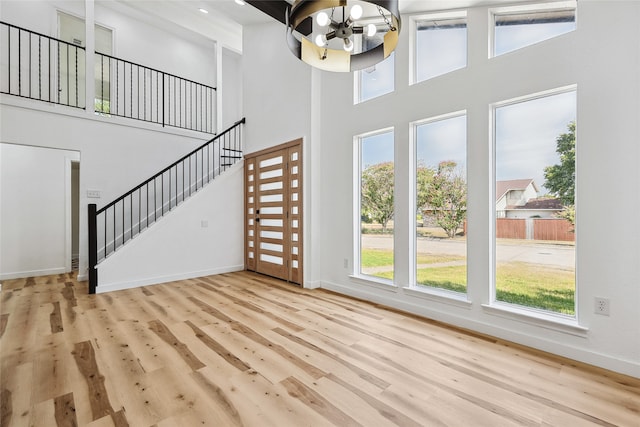 entrance foyer with light hardwood / wood-style flooring, high vaulted ceiling, and an inviting chandelier