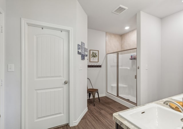 bathroom featuring a shower with shower door, sink, and hardwood / wood-style flooring