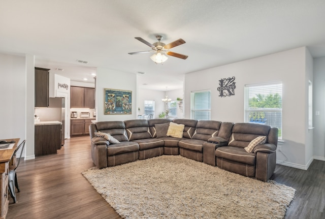 living room with dark hardwood / wood-style flooring and ceiling fan with notable chandelier