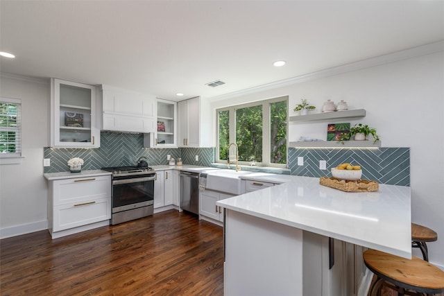 kitchen with appliances with stainless steel finishes, a breakfast bar area, white cabinets, kitchen peninsula, and crown molding