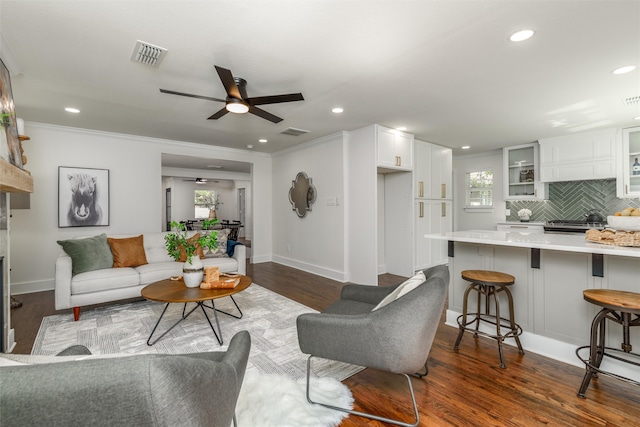 living room with dark wood-type flooring, ceiling fan, and a healthy amount of sunlight