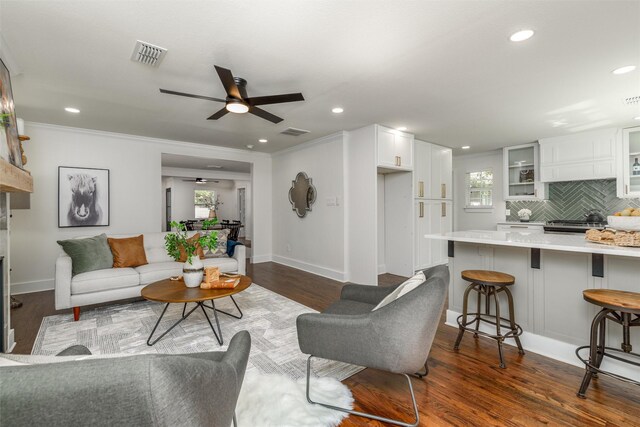 living room featuring ceiling fan, ornamental molding, and dark hardwood / wood-style flooring