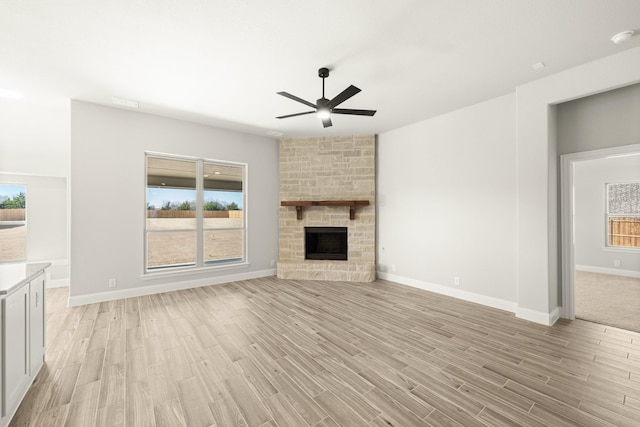 unfurnished living room featuring a stone fireplace, plenty of natural light, and light hardwood / wood-style floors