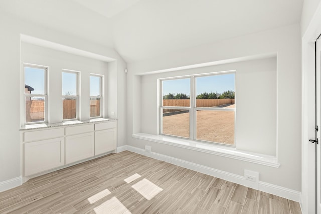 unfurnished room featuring lofted ceiling and light hardwood / wood-style floors