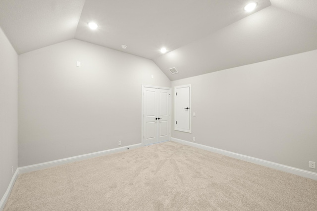 carpeted spare room with vaulted ceiling