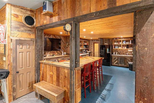 bar with black fridge and wood walls