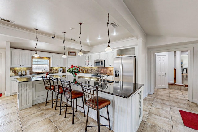 kitchen featuring decorative light fixtures, a breakfast bar, white cabinetry, stainless steel appliances, and a large island