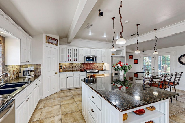 kitchen featuring white cabinetry, appliances with stainless steel finishes, beamed ceiling, a kitchen island, and sink