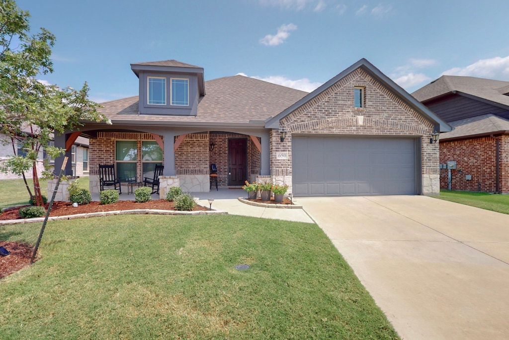 view of front of house featuring covered porch, a front yard, and a garage