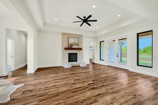 unfurnished living room with a fireplace, french doors, wood-type flooring, and ceiling fan