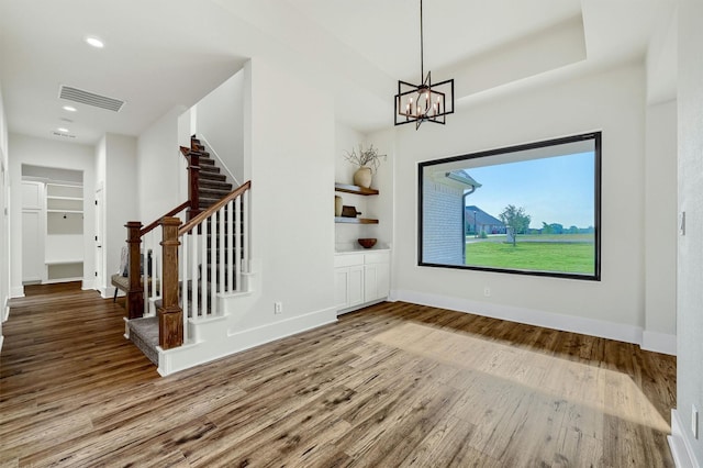 foyer entrance featuring an inviting chandelier, hardwood / wood-style floors, and a raised ceiling