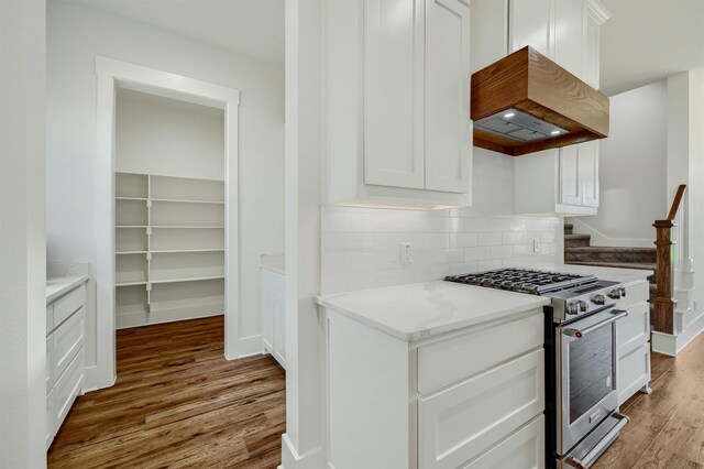 kitchen featuring light wood-type flooring, backsplash, high end stove, and white cabinetry