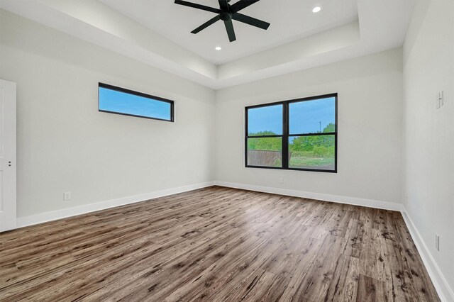 unfurnished room featuring hardwood / wood-style floors, ceiling fan, and a raised ceiling