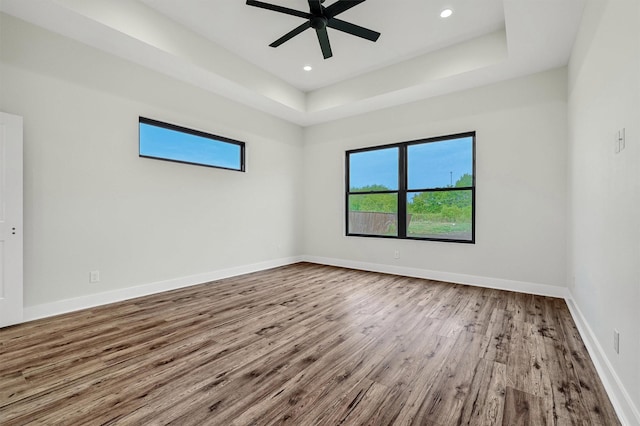 spare room featuring ceiling fan, wood-type flooring, and a tray ceiling