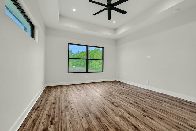 unfurnished room featuring ceiling fan, a raised ceiling, and wood-type flooring