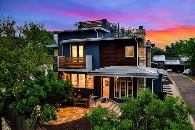 back house at dusk with a balcony