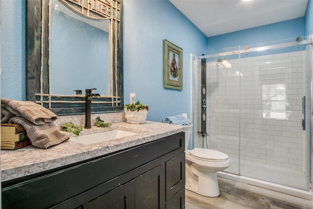 bathroom with a shower with door, wood-type flooring, vanity, and toilet