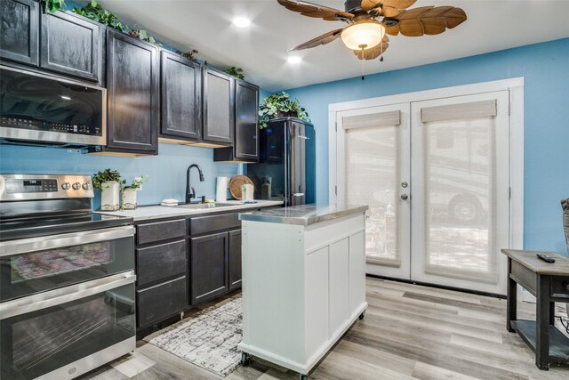 kitchen featuring appliances with stainless steel finishes, ceiling fan, sink, french doors, and light hardwood / wood-style floors